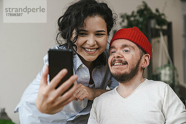 Glückliche Freundin und Freund  die zu Hause ein Selfie mit dem Smartphone machen