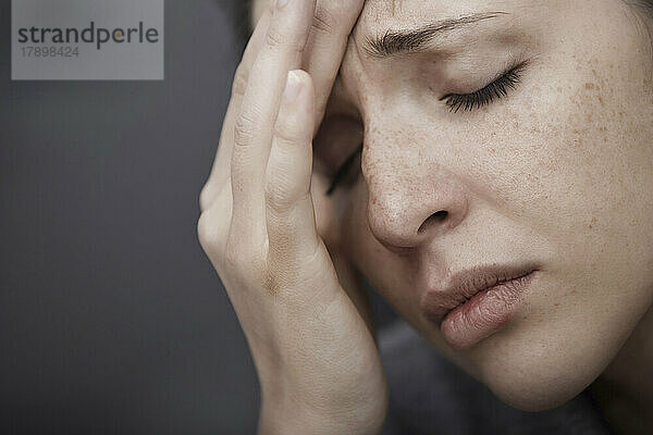 Traurige Frau  die unter Kopfschmerzen leidet