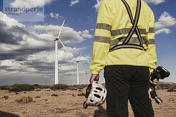 Techniker hält Arbeitsgerät und Helm im Windpark
