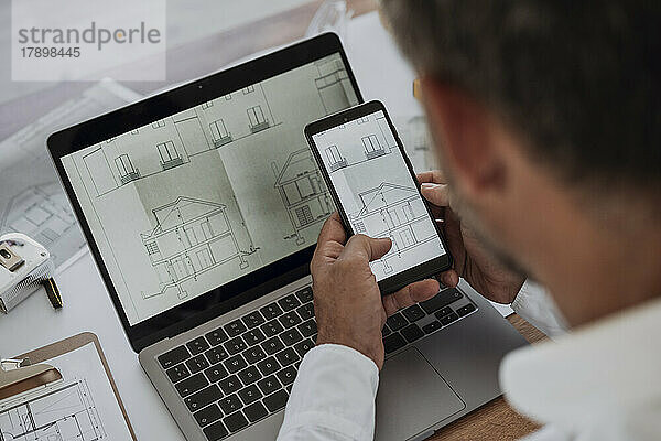 Hände des Architekten analysieren Zeichnung auf Mobiltelefon im Büro