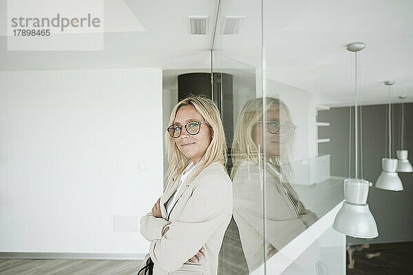 Businesswoman leaning against glass wall in office