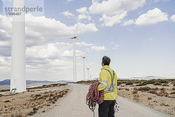 Ingenieur mit Seil betrachtet Windkraftanlagen im Windpark