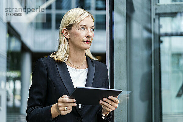 Blonde reife Geschäftsfrau steht mit Tablet-PC