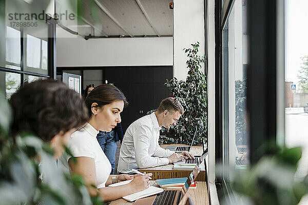 Geschäftsleute arbeiten im modernen Büro mit Laptop zusammen