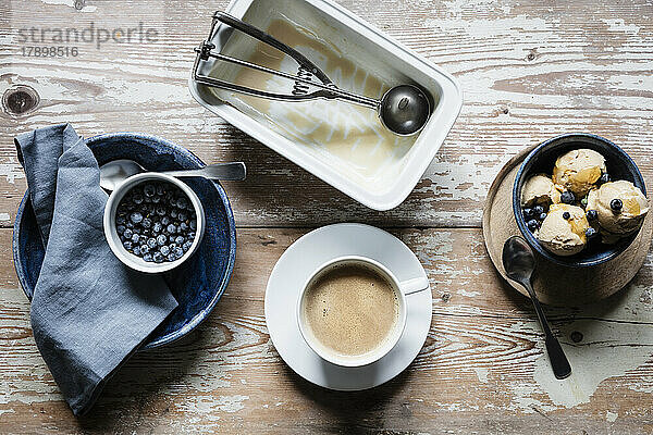 Tasse Kaffee  frische Blaubeeren und eine Schüssel hausgemachtes Erdnusseis