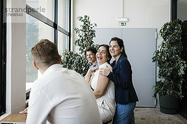 Geschäftsfrau lacht mit Kollegen im modernen Büro