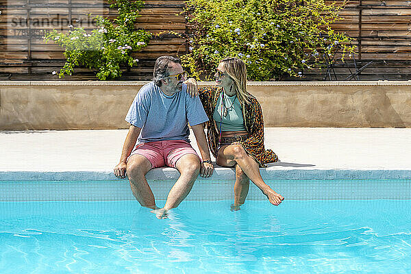 Glückliches älteres Paar  das an einem sonnigen Tag am Pool sitzt