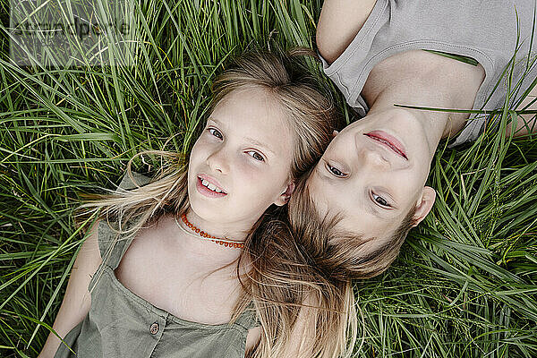 Brother and sister lying down on grass