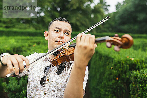 Nachdenklicher Mann spielt Geige im Park