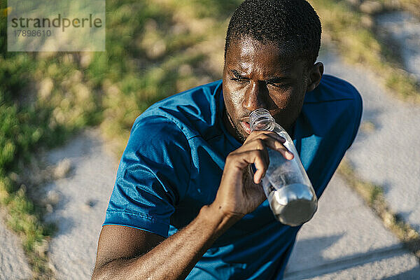 Mann trinkt an sonnigem Tag Wasser aus der Flasche