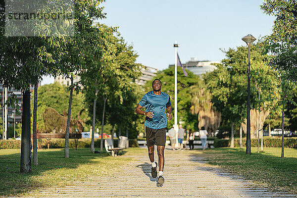 Junger Mann joggt an sonnigem Tag im Park
