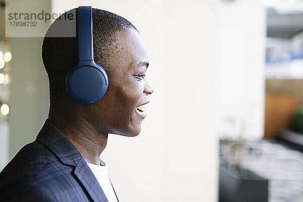 Glücklicher junger Mann mit kabellosen Kopfhörern  der Musik hört