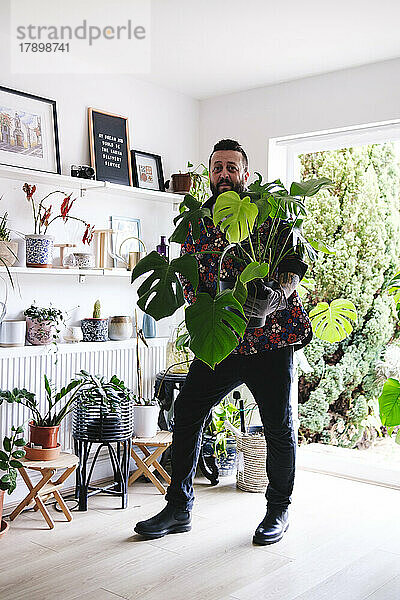 Mann steht mit Topfpflanze zu Hause
