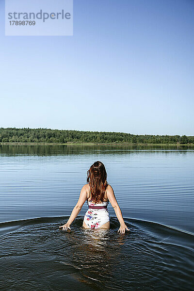 Frau geht unter blauem Himmel im See spazieren