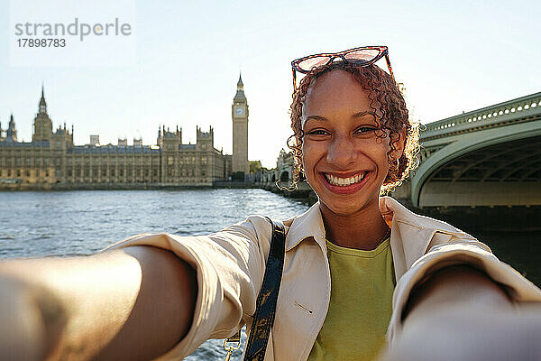 Glückliche junge Frau  die ein Selfie vor der London Bridge macht