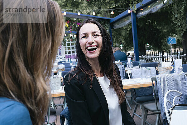 Mature businesswoman laughing with colleague in restaurant