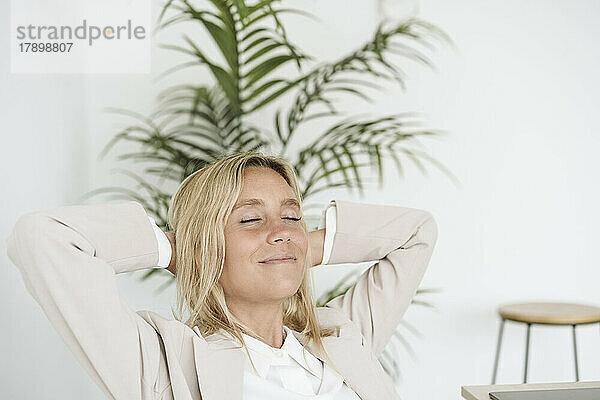 Entspannte Geschäftsfrau mit geschlossenen Augen im Büro