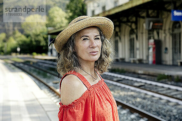Frau mit Hut wartet am Bahnhof auf den Zug