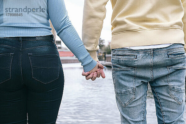 Young couple holding hands together in front of river
