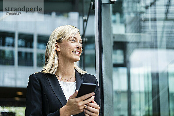 Lächelnde blonde Geschäftsfrau mit Mobiltelefon