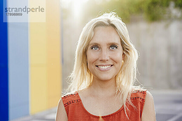 Glückliche junge Frau mit blonden Haaren an einem sonnigen Tag