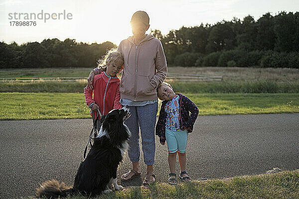 Mutter mit Töchtern und Hund stehen zusammen