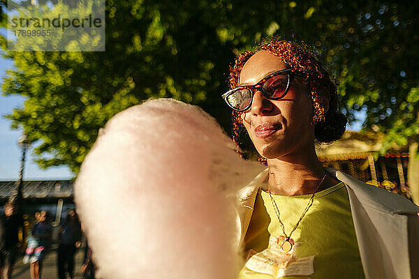 Junge Frau mit Sonnenbrille genießt Zuckerwatte