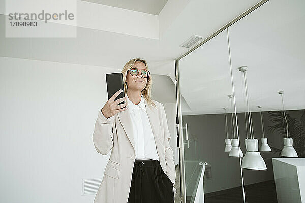 Geschäftsfrau im modernen Büro mit Mobiltelefon