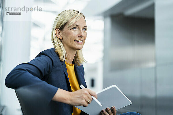Lächelnde Geschäftsfrau sitzt mit Tablet-PC
