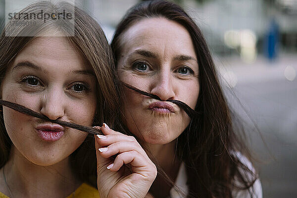 Zwei Frauen haben Spaß daran  Schnurrbart aus Haaren zu machen