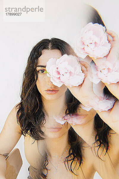 Mehrfachbelichtung einer jungen Frau  die eine rosa Blume über dem Auge hält