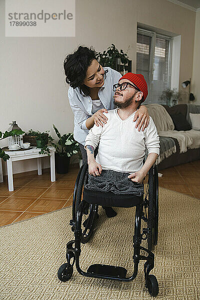 Lächelnde Frau schaut ihren Freund im Rollstuhl an