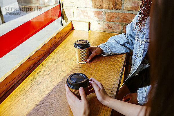 Junge Freunde mit Kaffeetasse sitzen am Tisch im Café