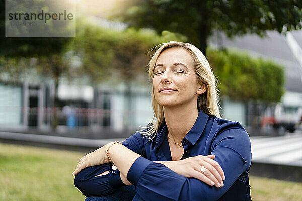 Geschäftsfrau mit geschlossenen Augen sitzt im Park