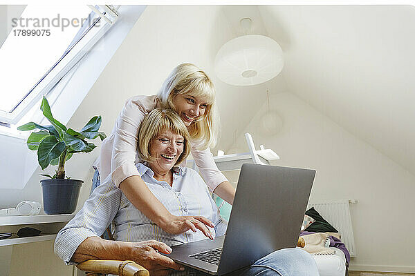 Glückliche blonde Frau mit Mutter  die zu Hause Laptop benutzt