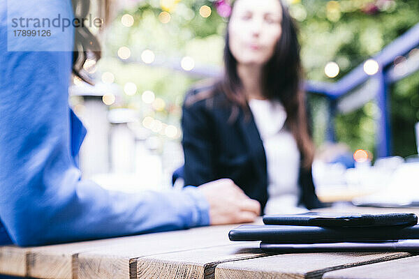 Geschäftsfrau sitzt neben einem Stapel Smartphones auf dem Tisch im Restaurant