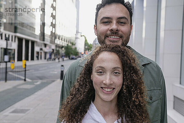 Smiling woman with curly hair standing in front of friend