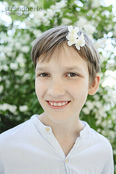 Glücklicher Junge mit Jasminblüte im Haar