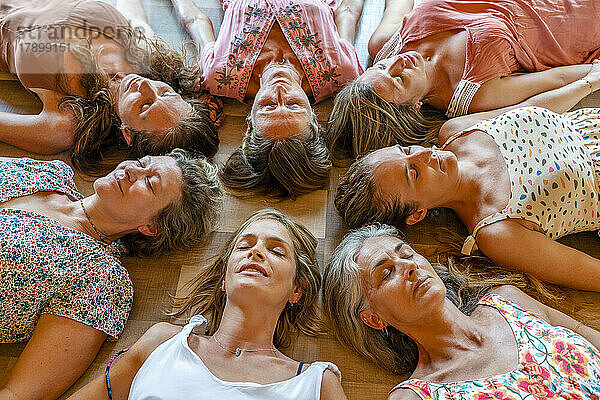 Frauen mit geschlossenen Augen liegen zusammen auf dem Boden