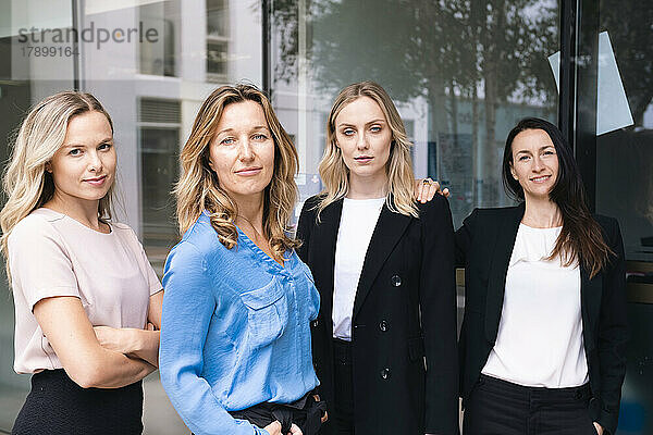 Confident businesswomen standing together outside glass wall