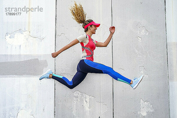 Glückliche Sportlerin springt vor die Wand