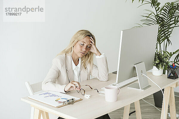 Müde Geschäftsfrau sitzt am Schreibtisch im Büro