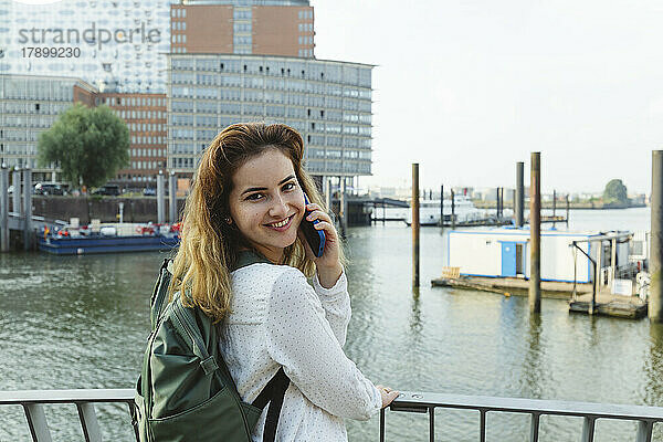 Glückliche Frau  die im Hamburger Hafen telefoniert