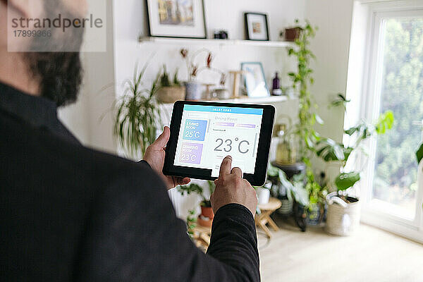 Mann regelt die Raumtemperatur über einen Tablet-PC zu Hause