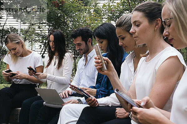 Geschäftskollegen nutzen Smartphone und Laptop und sitzen zusammen im Büropark
