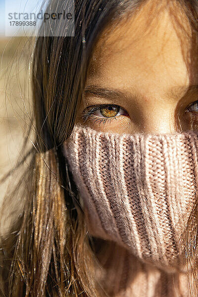 Mädchen mit braunen Augen  die an einem sonnigen Tag ihr Gesicht bedecken