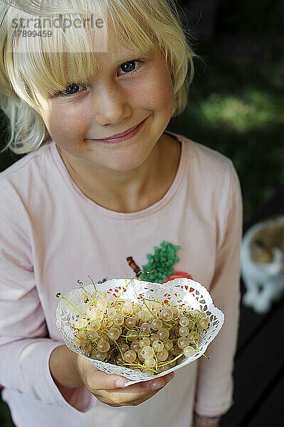 Porträt eines kleinen Mädchens mit frisch gepflückten Johannisbeeren
