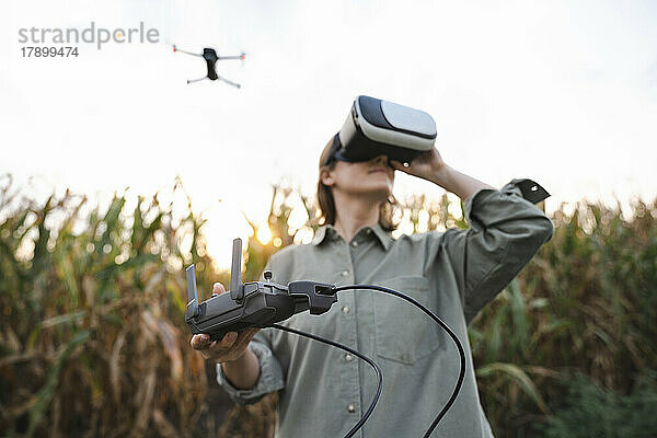 Frau mit VR-Brille und ferngesteuerter Drohne im Maisfeld