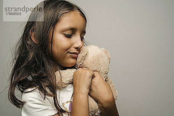 Smiling girl embracing teddy bear