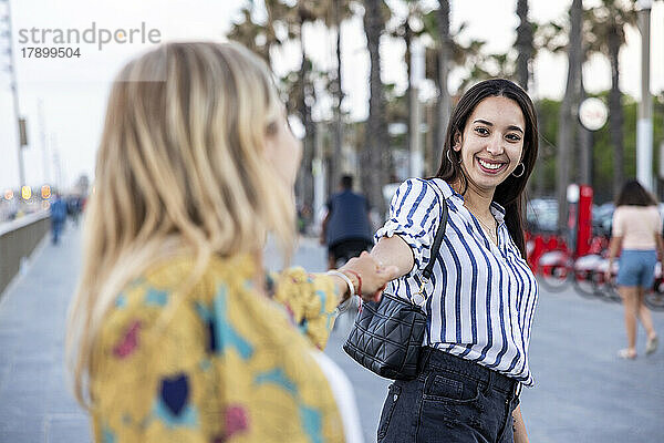 Glückliche Frau hält Händchen eines Freundes an der Promenade